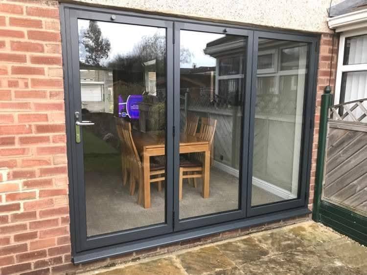 Anthracite grey bi-fold doors opening onto garden patio